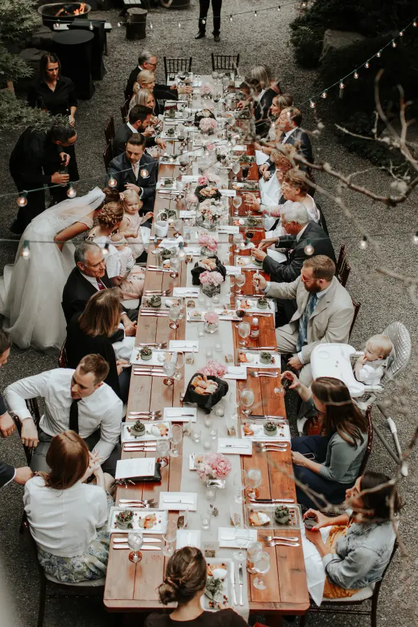 Outdoor wedding reception table with floral centerpieces and string lights in Pacific Northwest. Lovely Events.