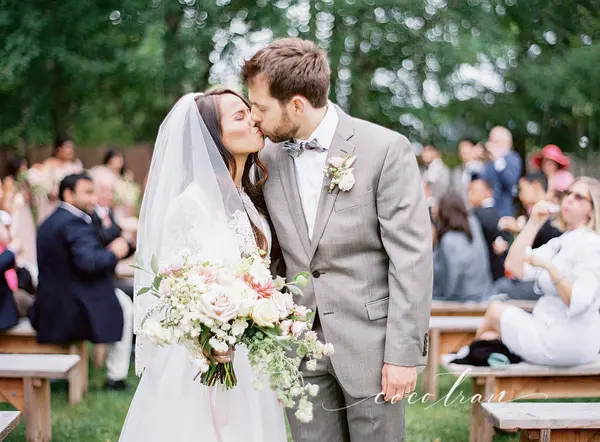 Bride and groom kissing at outdoor Pacific Northwest wedding ceremony with garden setting. Lovely Events.