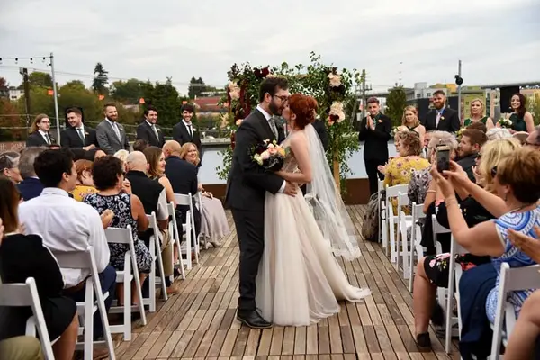 Bride and groom kissing at Pacific Northwest waterfront wedding ceremony on deck. Lovely Events.