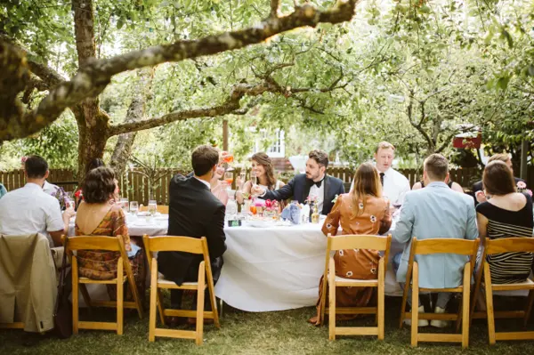 Bride and groom toasting at outdoor wedding reception under trees in Pacific Northwest. Lovely Events.